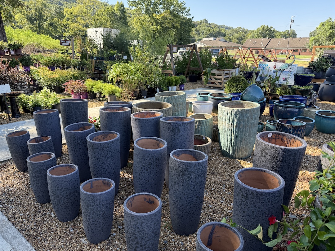 Textured stone-look tall planters in grey and teal finishes on gravel display