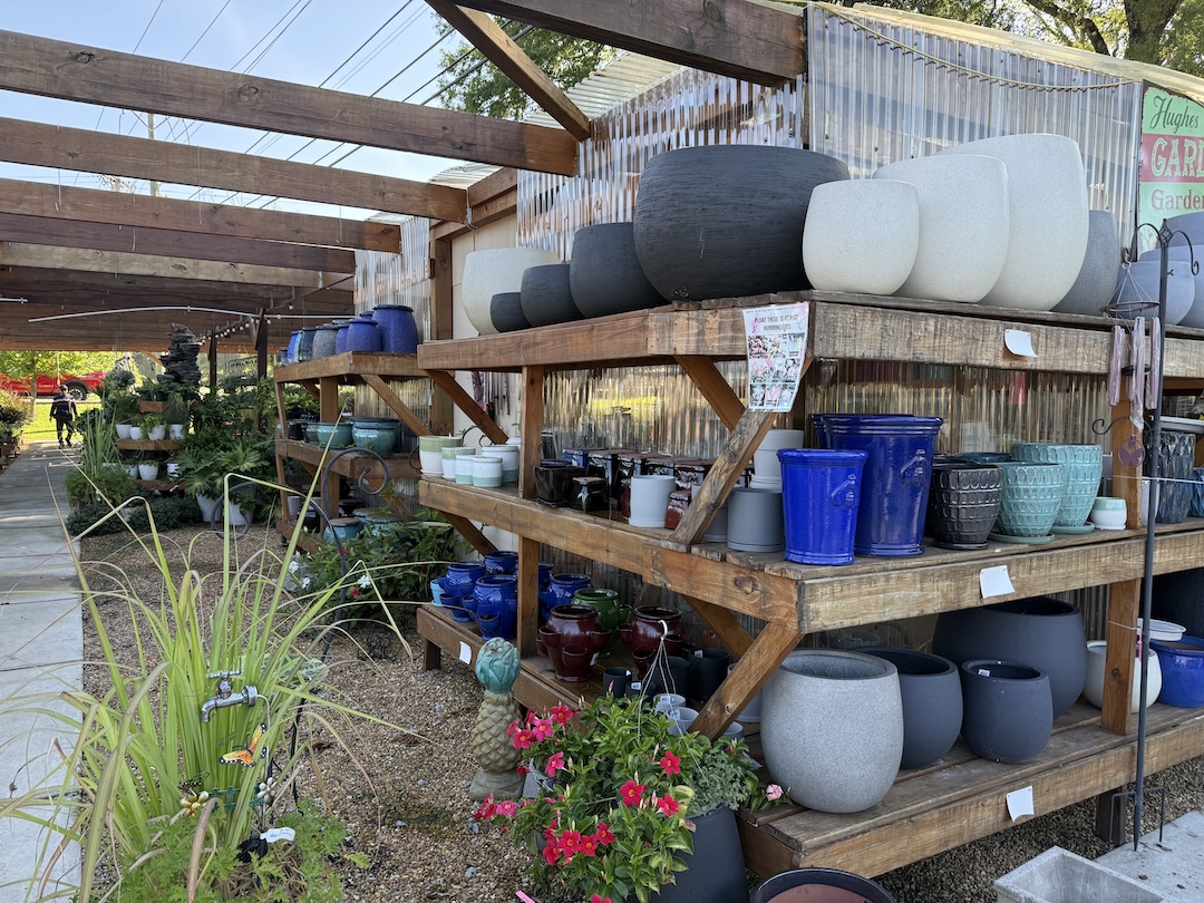 Large selection of colorful glazed ceramic pots on wooden display shelves