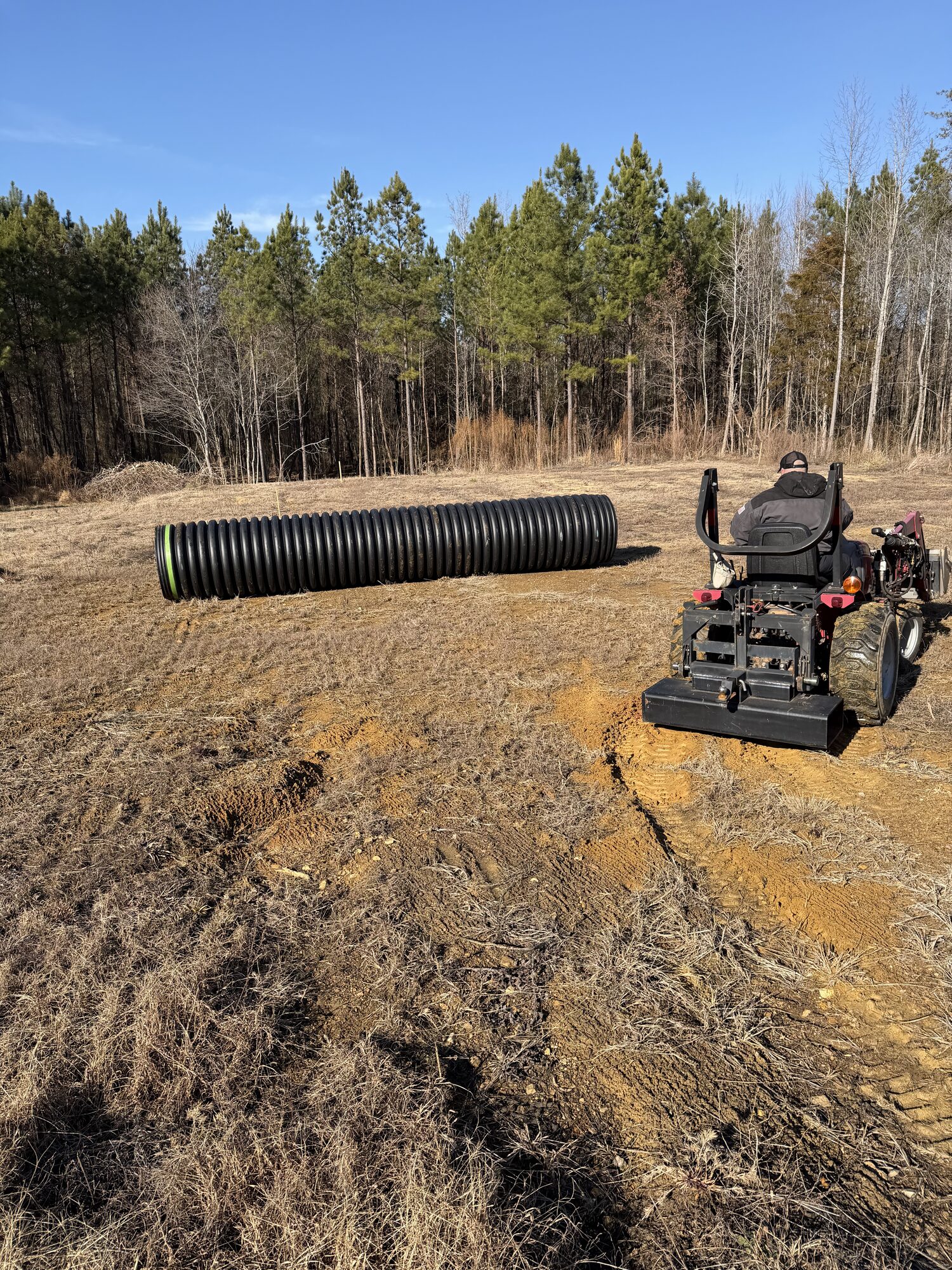 Large corrugated drainage pipe staged for installation on a rural North Carolina property