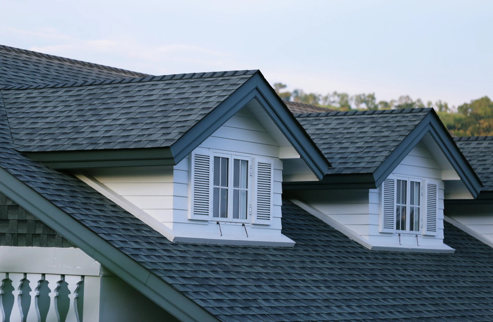 Professional dark shingle roofing with white siding home exterior