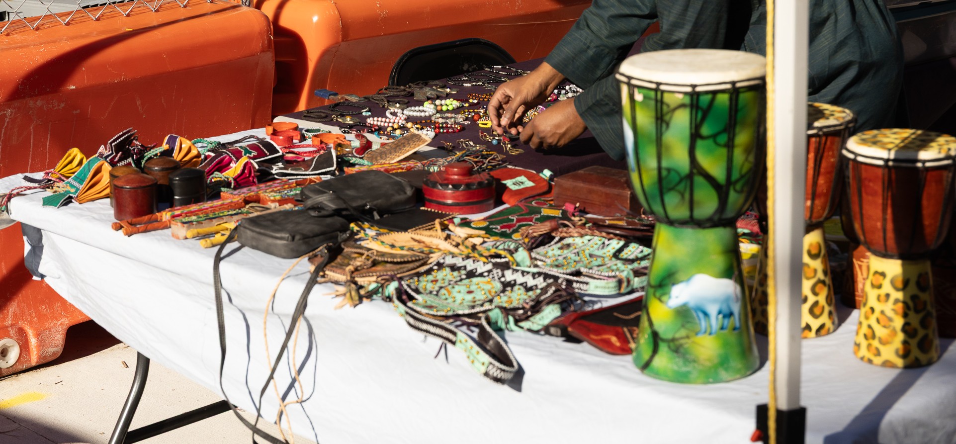Artisan vendor displaying handcrafted African djembe drums, beaded jewelry, and leather crafts at Taste of Africa