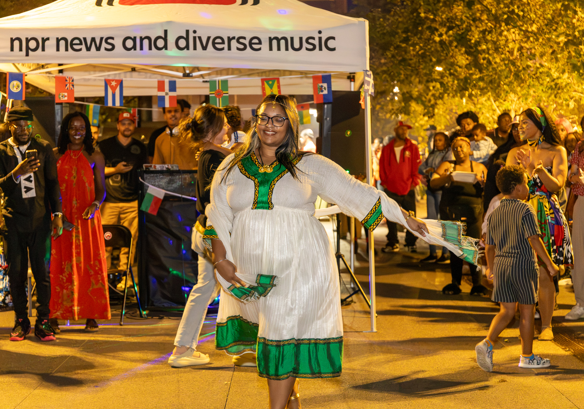 Dancer in traditional white and green dress smiling and moving to the music