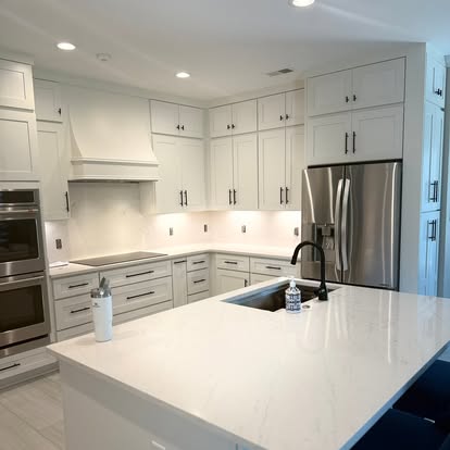 Contemporary white kitchen remodel with quartz waterfall island, custom range hood, and double wall ovens
