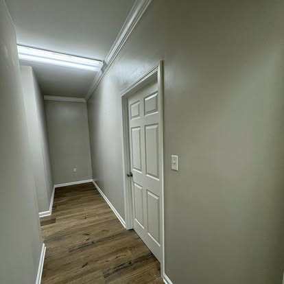 Hallway renovation featuring luxury plank wood flooring, new doors, crown molding, and fresh paint