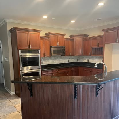 Expansive kitchen renovation with custom warm wood cabinetry, granite countertops, and breakfast bar