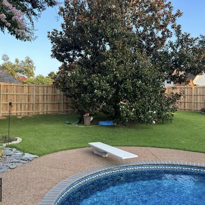 Tall cedar perimeter privacy fence enclosing in-ground swimming pool backyard