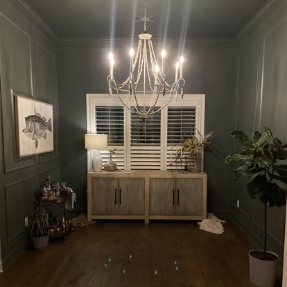 Deep green dining room featuring full wainscot panel molding and crown trim