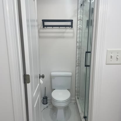 Complete bathroom remodel with frameless glass shower enclosure, matte black fixtures, and new tile