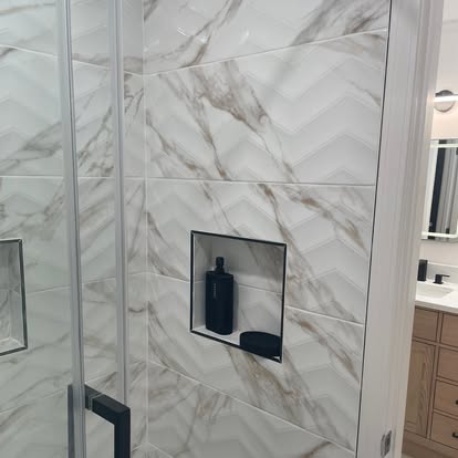 Custom shower remodel with chevron marble porcelain tile and integrated shampoo shelf niche