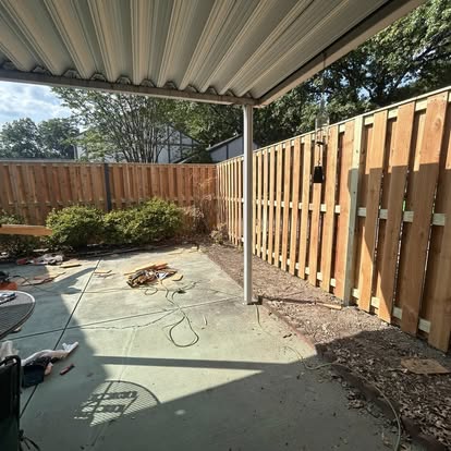 Sturdy wood privacy fence with heavy timber framing and concrete patio
