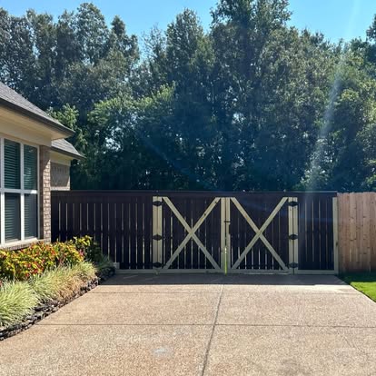 Two-tone dark stain privacy fence with double-drive security gate and heavy timber posts