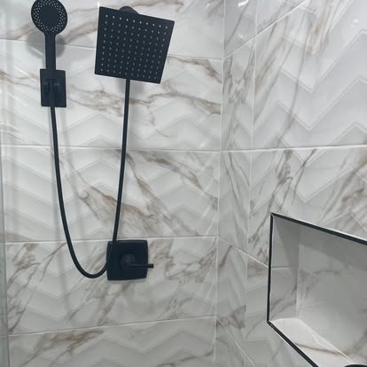Walk-in shower renovation with marble herringbone tile, matte black rain showerhead, and recessed niche