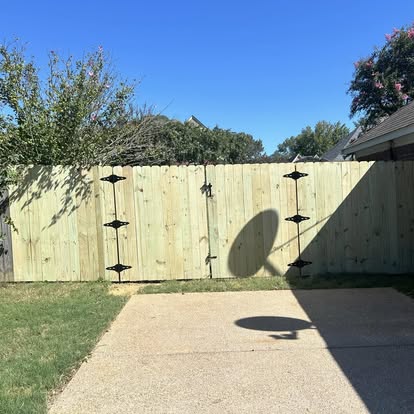 New wooden privacy fence with heavy-duty black decorative gate hinges and latch