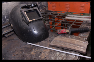 Welding Equipment — Helmet & Electrode on Workbench