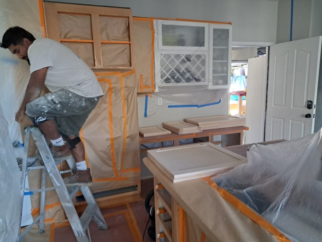 Our craftsman carefully preparing cabinet surfaces for refinishing. Meticulous masking and preparation ensure a flawless final result.