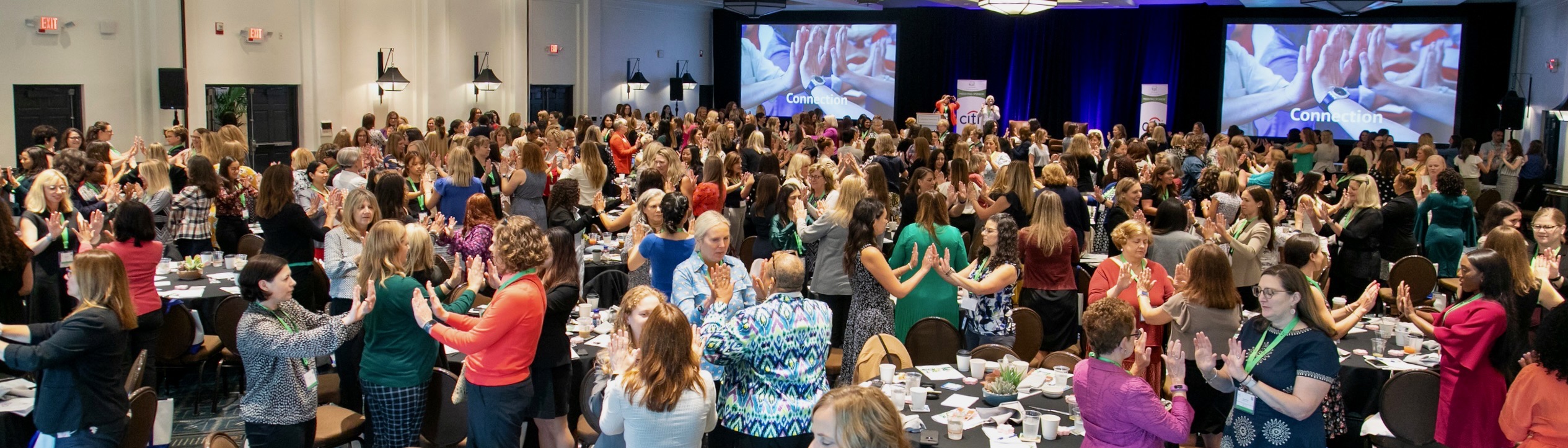 Audience participating in a leadership workshop with hands raised in connection