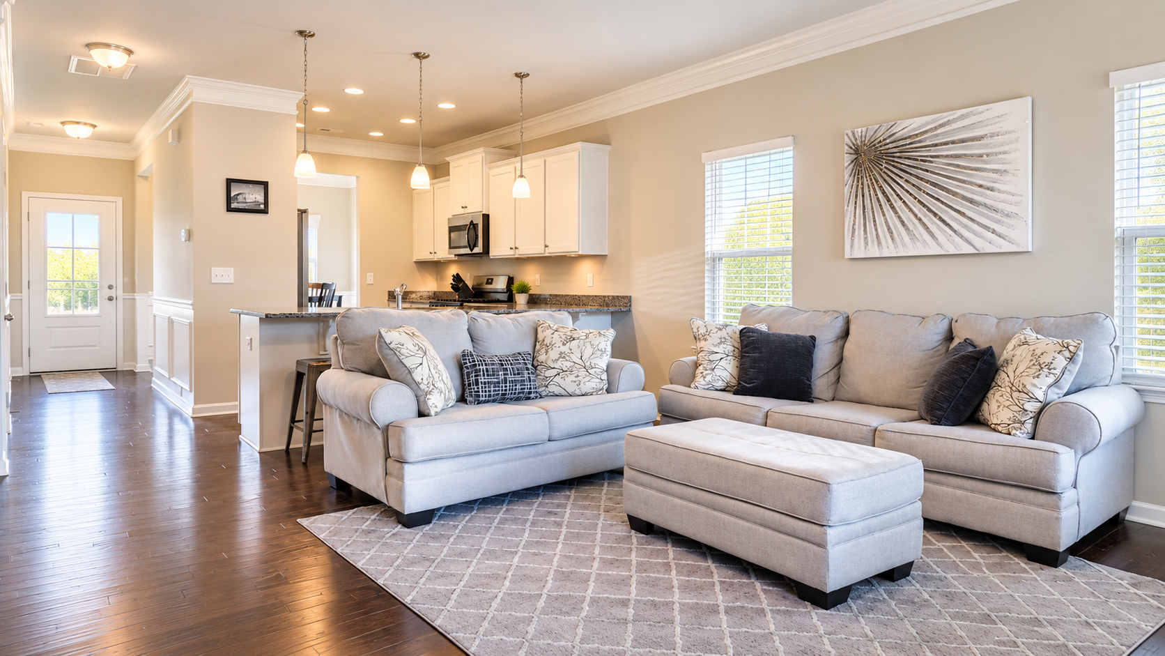 Bright, clean modern living room and open kitchen with natural lighting and neutral furnishings
