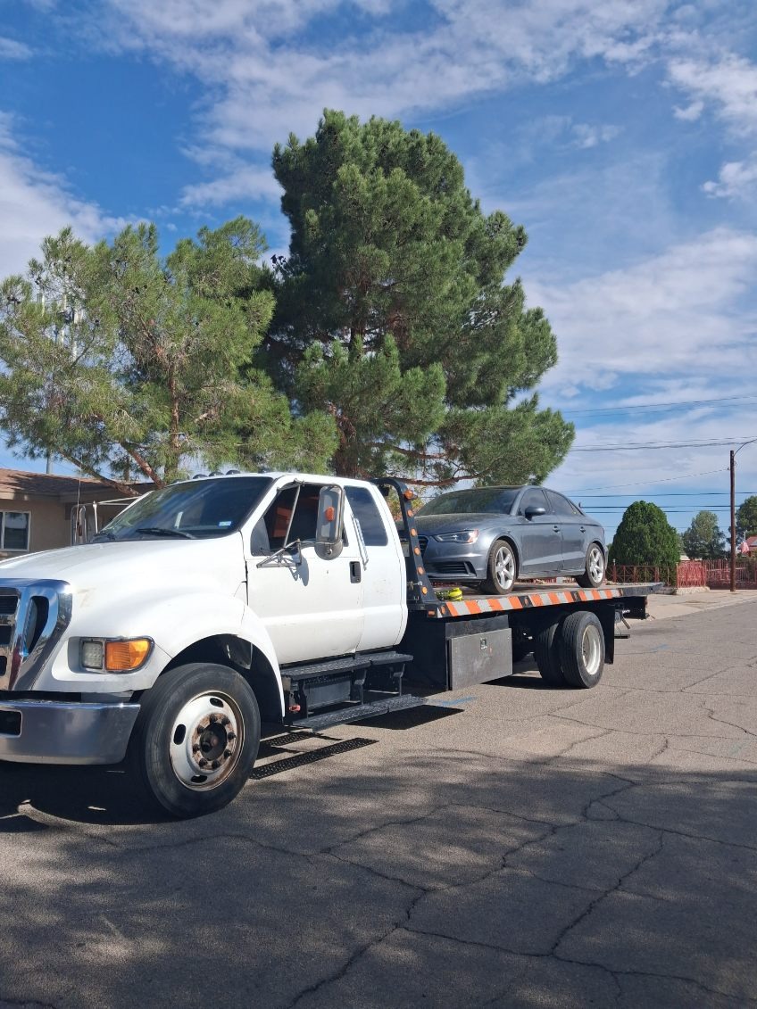 Professional flatbed towing service for gray sedan vehicle transport