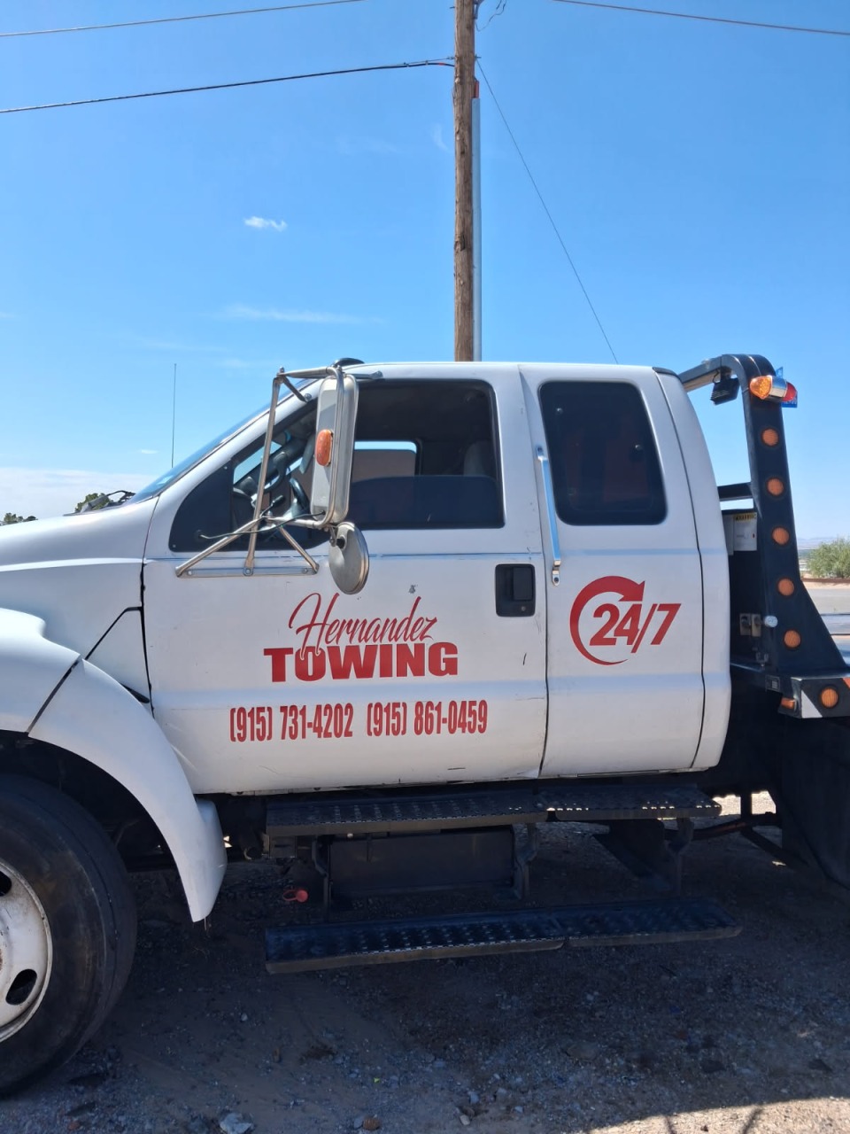 White Hernandez Towing service truck with 24/7 emergency branding and contact numbers on door