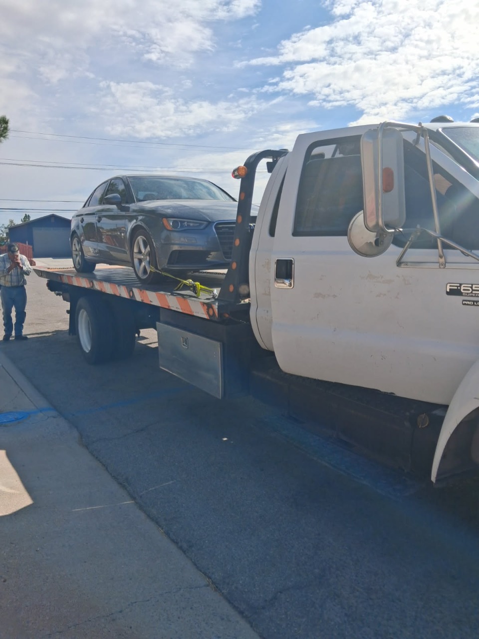 Gray luxury sedan carefully secured on flatbed tow truck for damage-free transport