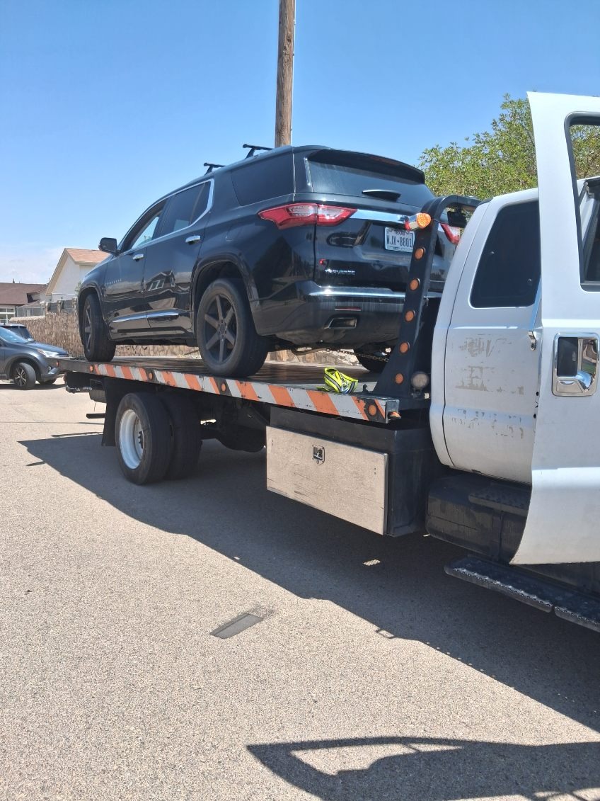 Black SUV securely loaded on tow truck bed for safe transport