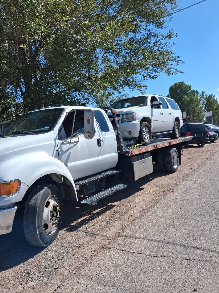 White Hernandez Towing flatbed truck transporting a white SUV in El Paso, Texas