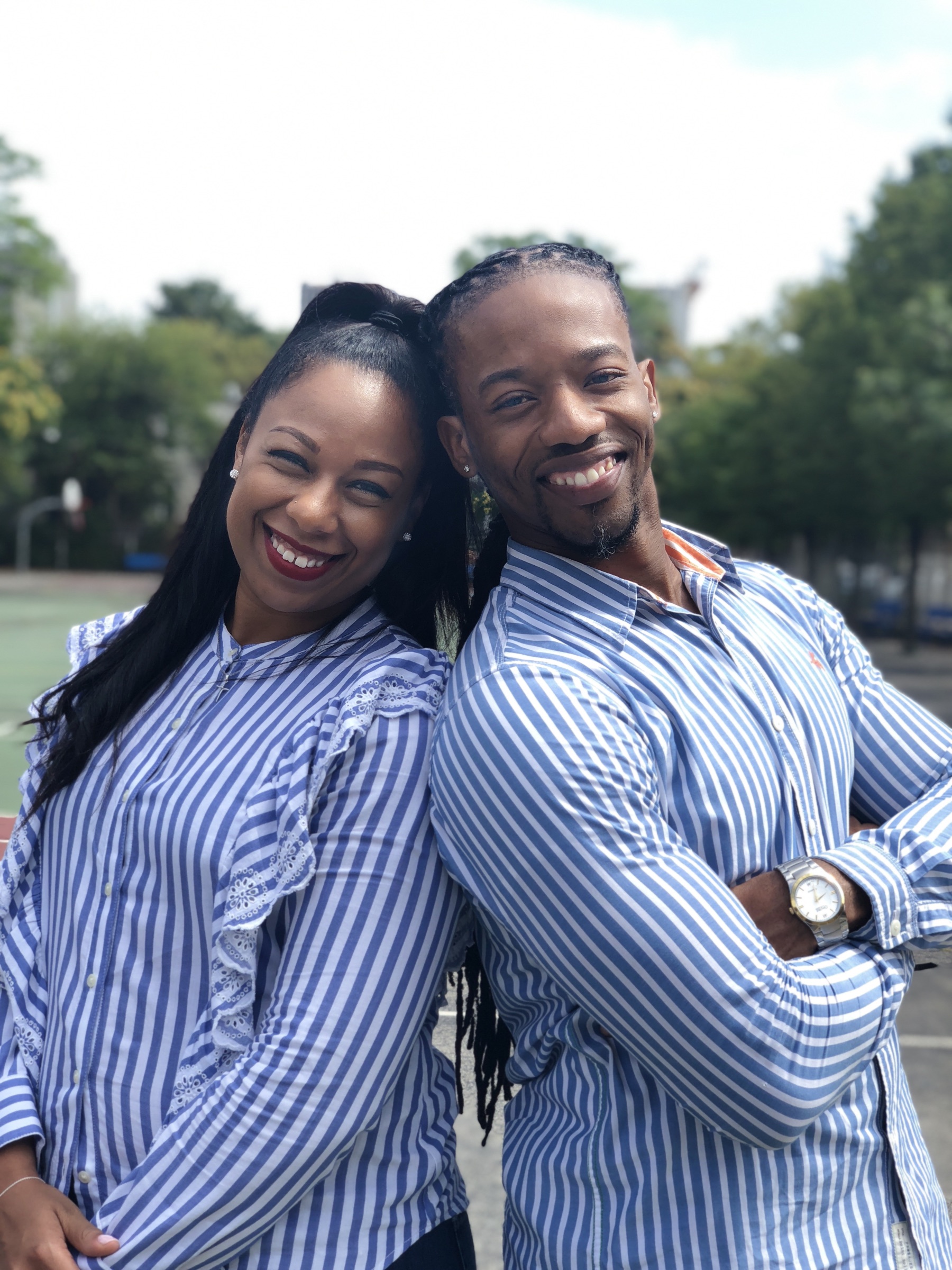 Kes and Jaz smiling back-to-back in matching blue shirts.