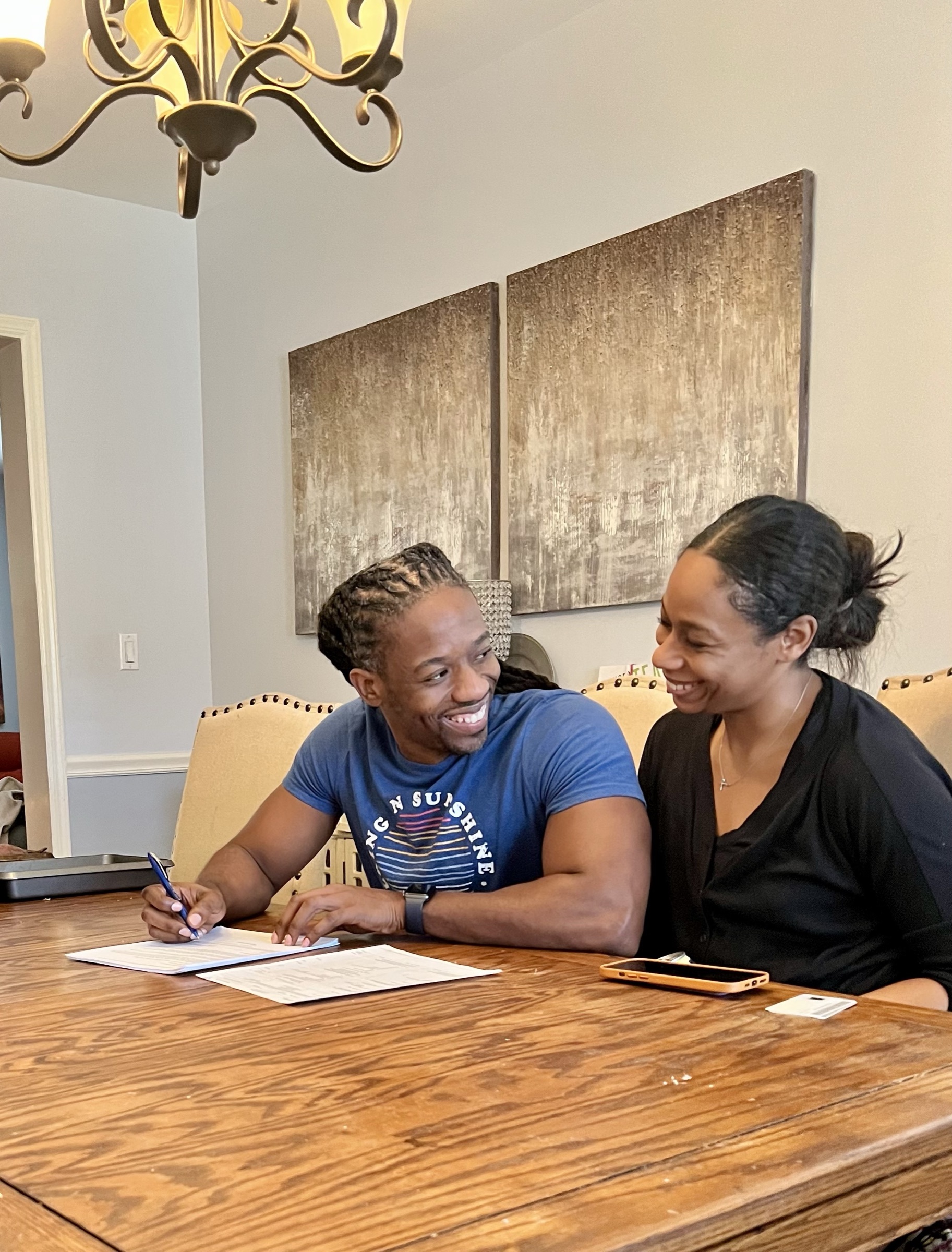 Kes and Jaz talking together at a table with papers and a pen.