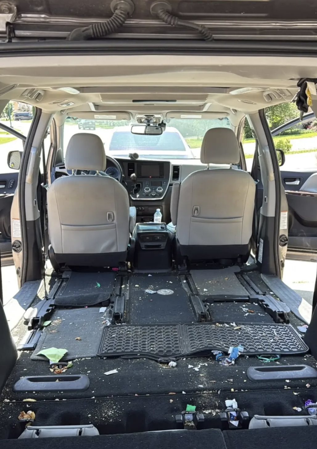 Heavily soiled minivan interior with trash, debris, and dirty seat tracks before detailing in Savannah