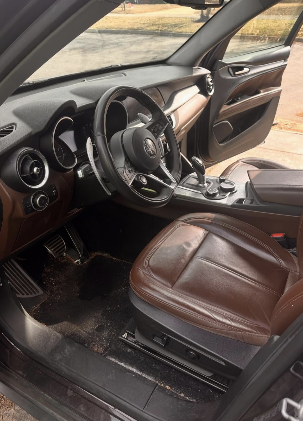 Dirty Alfa Romeo interior with dusty leather seats, grimy floor mats, and neglected surfaces before detailing