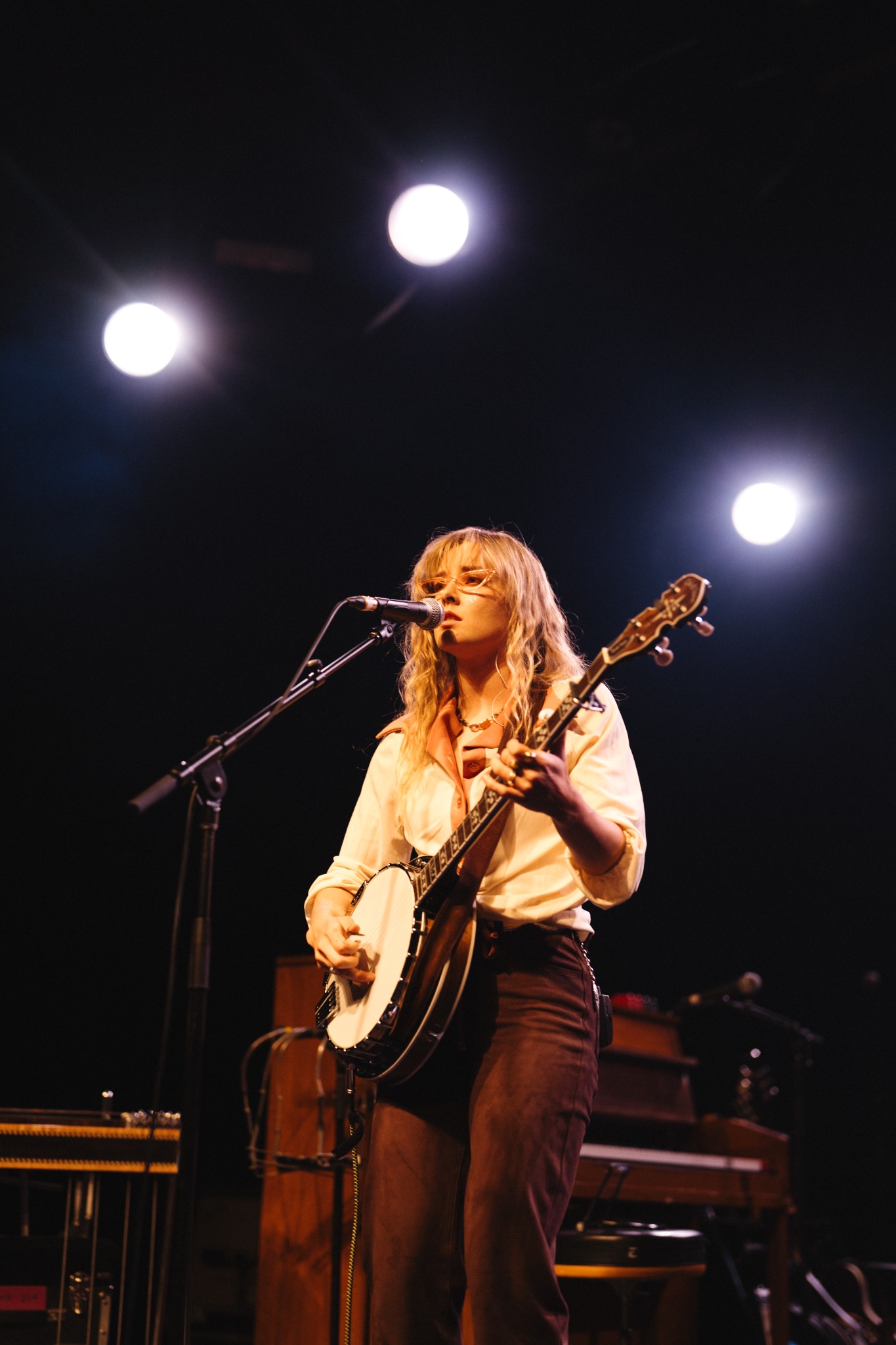 Brenna MacMillan singing in pink collar shirt and glasses at El Rey Theatre in Los Angeles