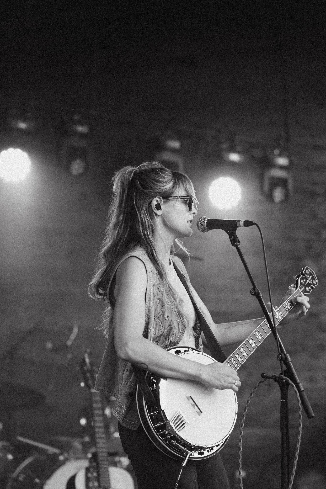 Brenna MacMillan playing banjo outdoors in embroidered vest and sunglasses at Historic Scoot Inn in Austin