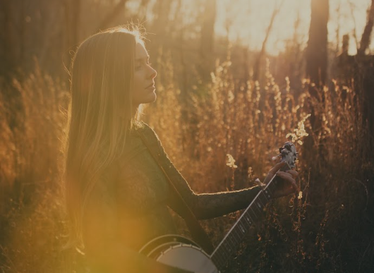 Brenna MacMillan with banjo in golden field light