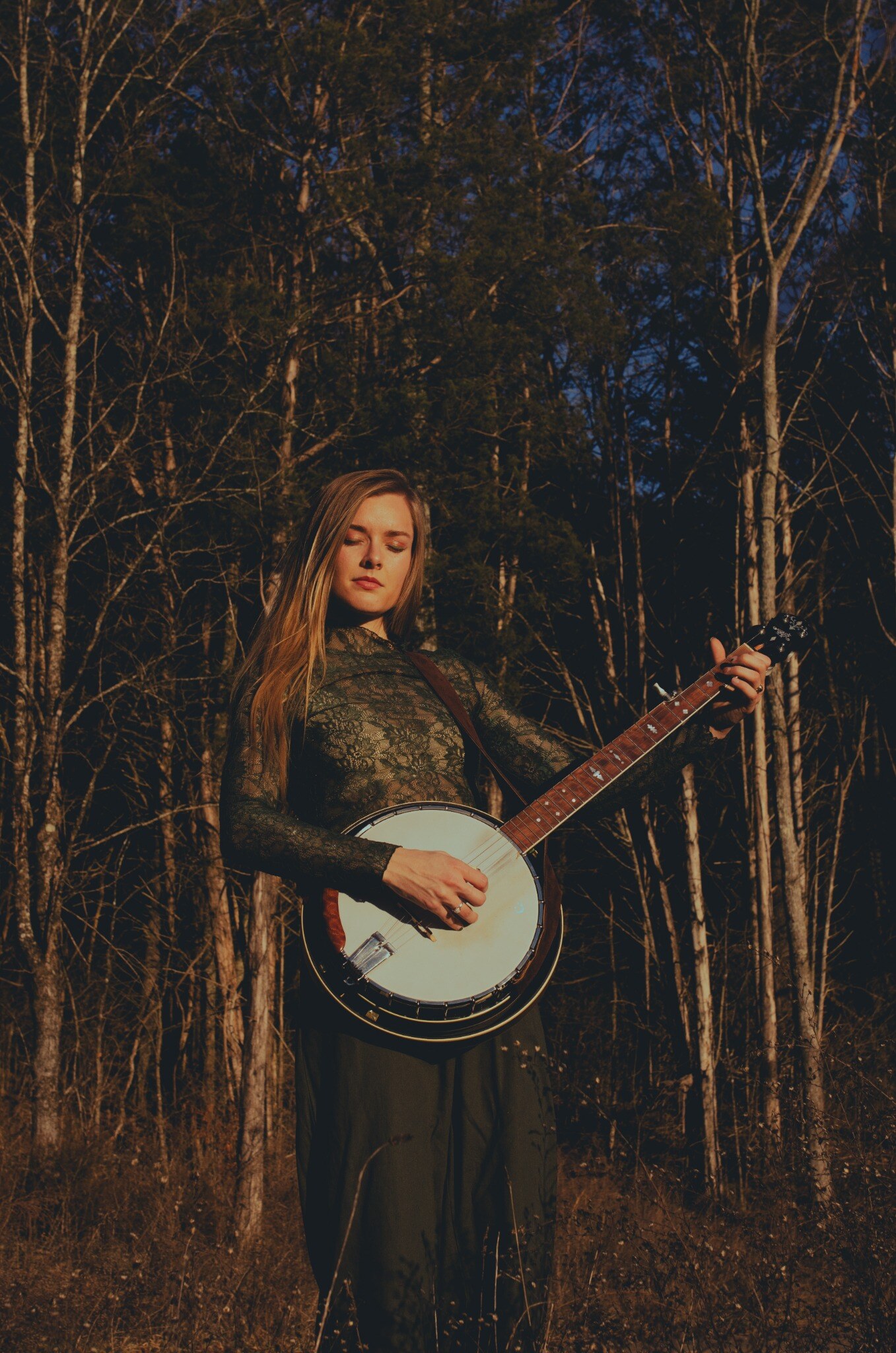 Brenna MacMillan playing banjo among trees
