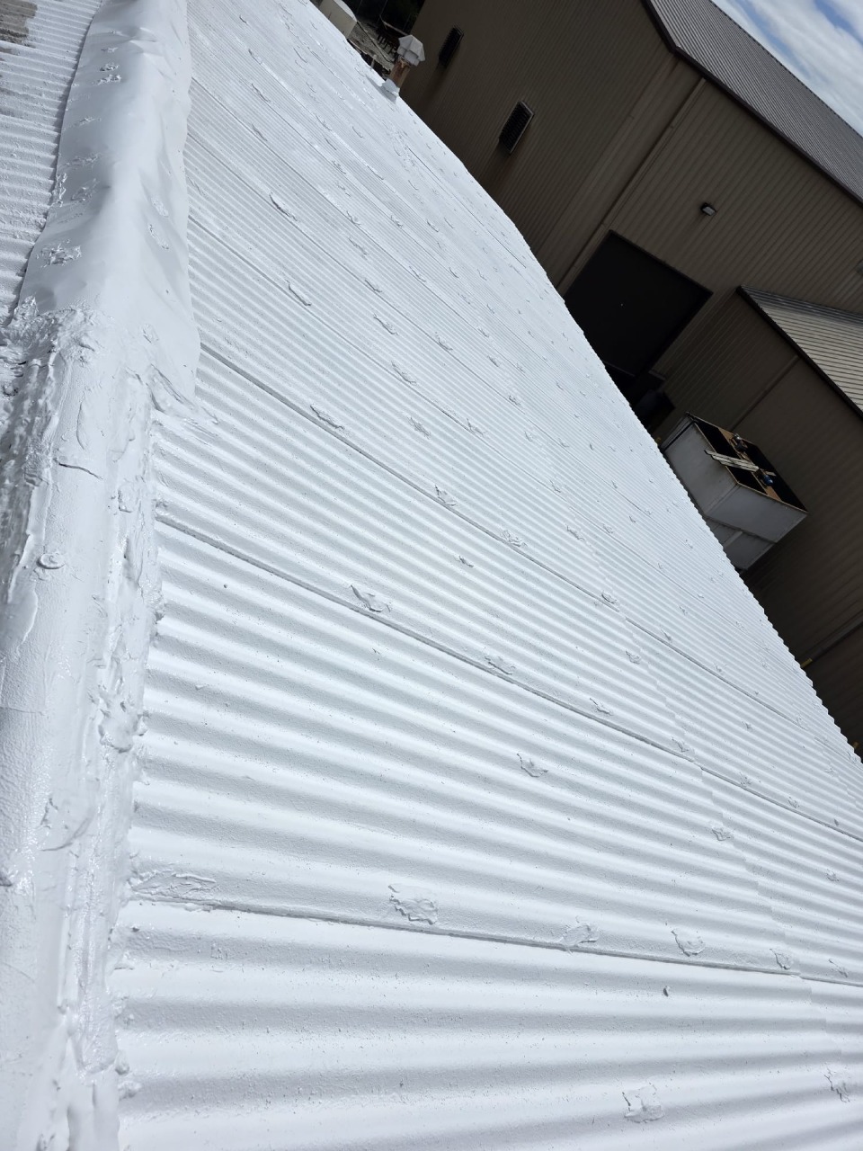Close-up detail of white painted corrugated metal roof showing clean ridges and professional edge finishing