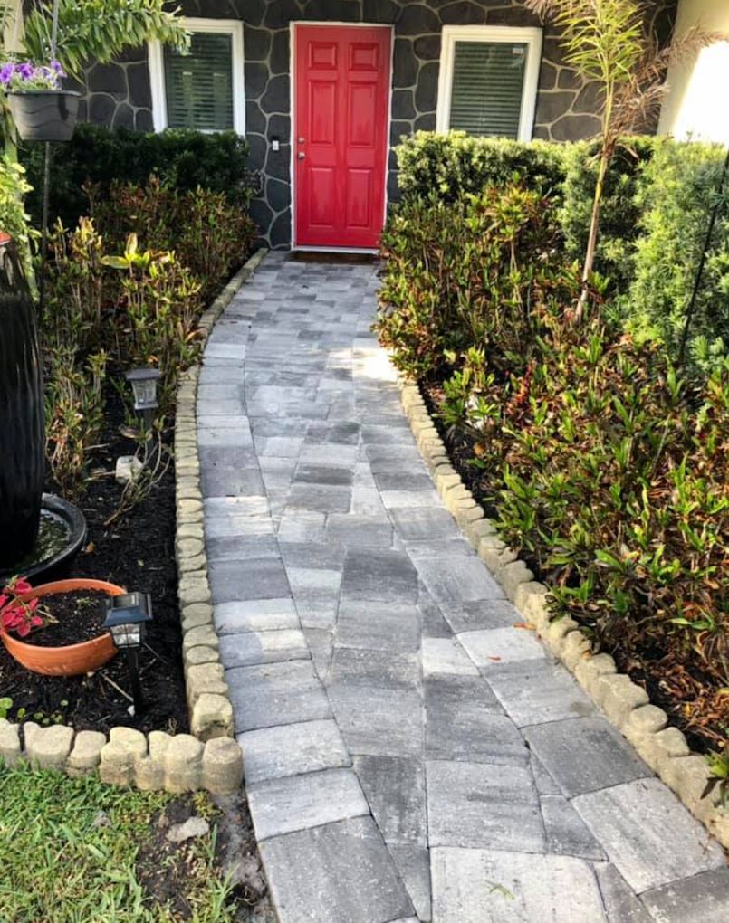 Gray paver walkway entry path with stone edging leading to red front door
