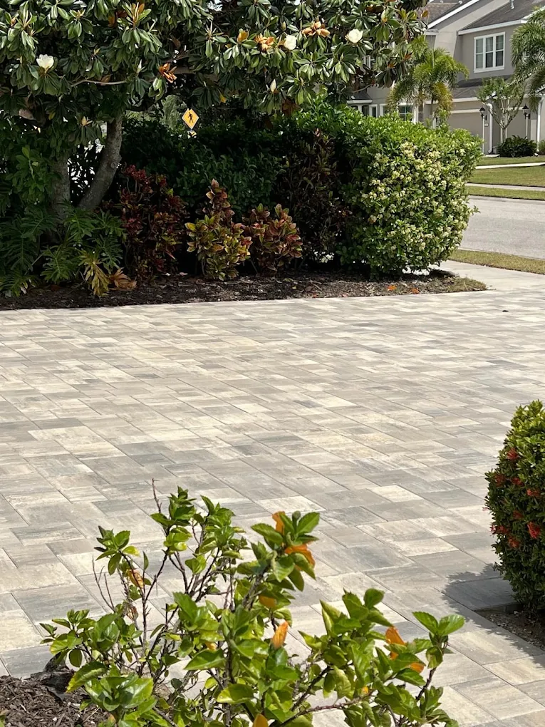 Gray concrete paver driveway with multi-tone pattern and landscaping