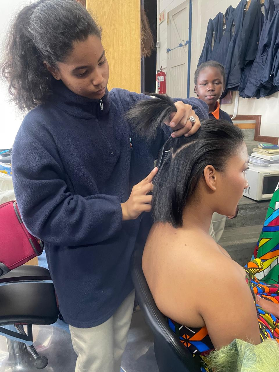 Student practicing hairstyling on a model during training session