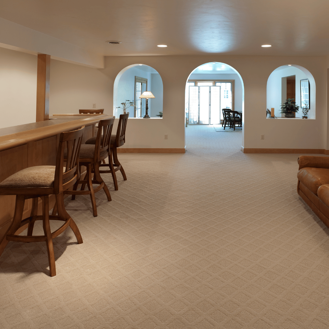 Spacious finished basement entertainment area with arched doorways, built-in bar with seating, and leather couch