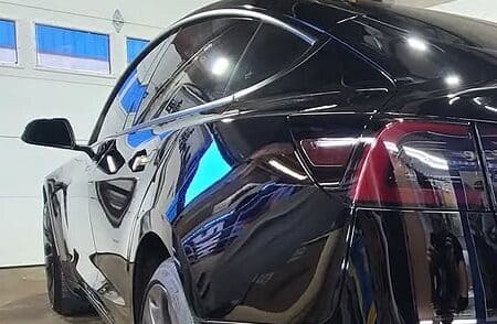 Black Tesla after ceramic coating showing mirror-like gloss and deep reflections