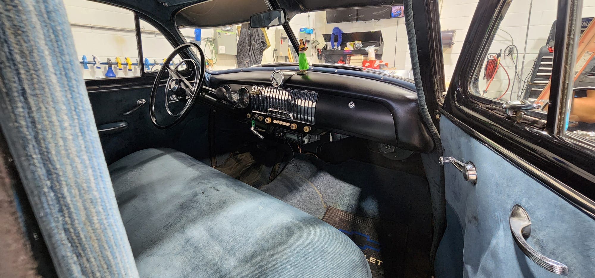 Detailed classic car interior with restored blue upholstery, dashboard, and door panels