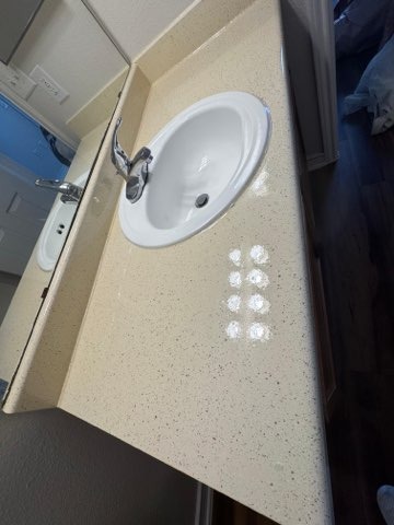 New bathroom vanity with beige speckled countertop and white sink installation