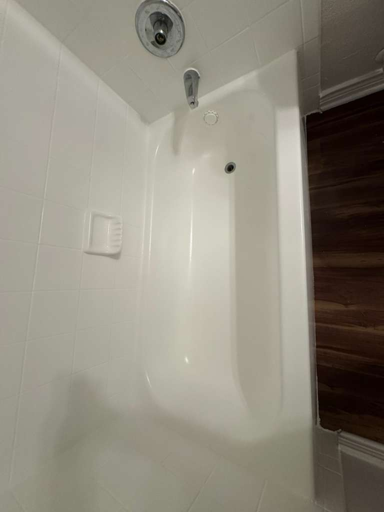 Bathtub after professional refinishing - pristine sparkling clean white surface with fresh tile work by Paint And Remodeling Aguilar LLC
