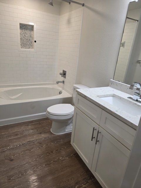 Renovated bathroom with white subway tiles and wood-look vinyl flooring