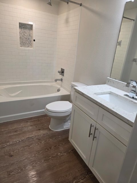Bathroom before remodeling - original white tile walls, light wood flooring and basic white vanity by Paint And Remodeling Aguilar LLC