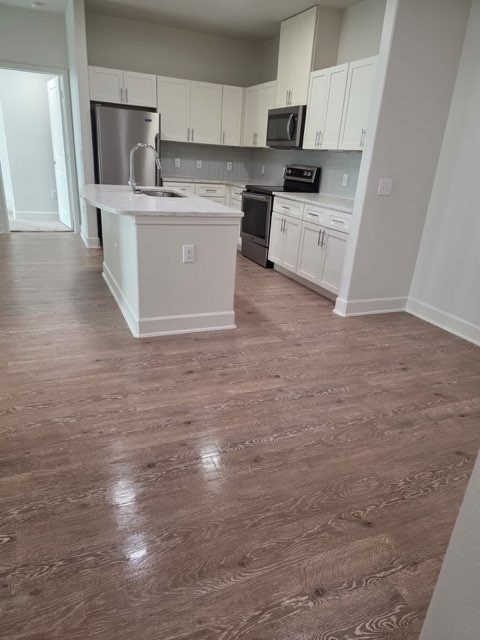 Completed modern kitchen remodel with white cabinets and island by Paint And Remodeling Aguilar