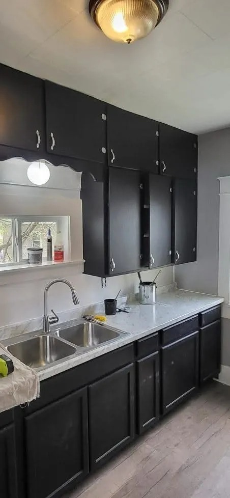 Modern black painted kitchen cabinets with white quartz countertops and stainless steel sink