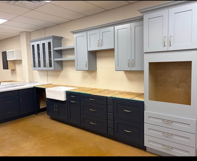 Two-tone gray and navy blue kitchen cabinet showroom display with farmhouse sink