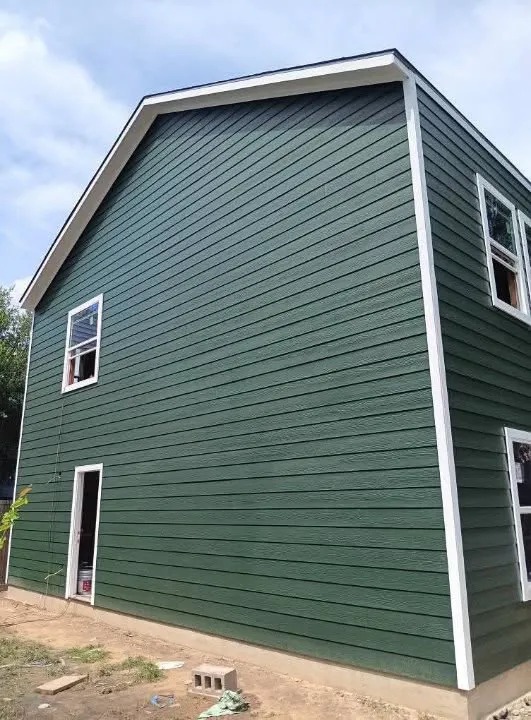 Two story house with forest green horizontal siding paint job and white trim around windows and doors
