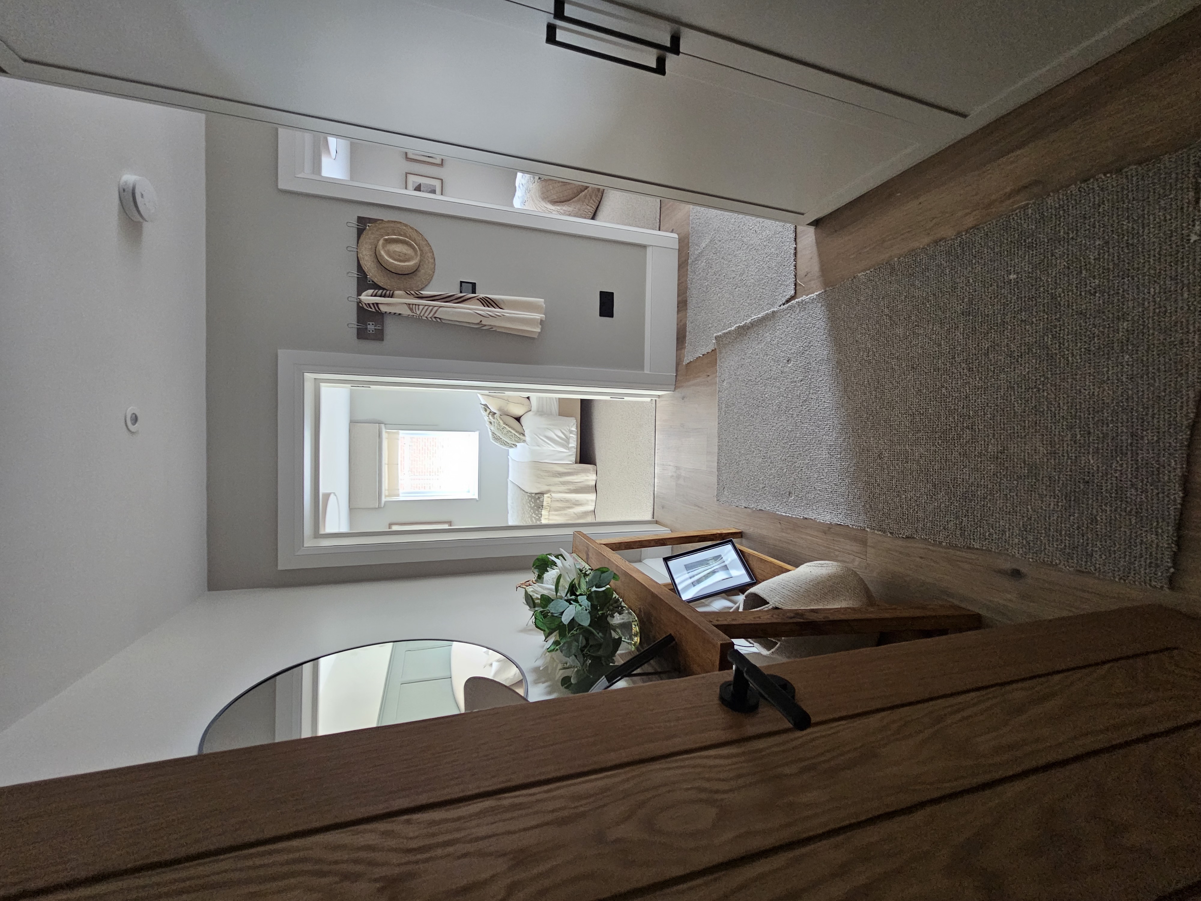Completed DWELLUX loft landing with oak staircase handrail, round mirror and panelled doors